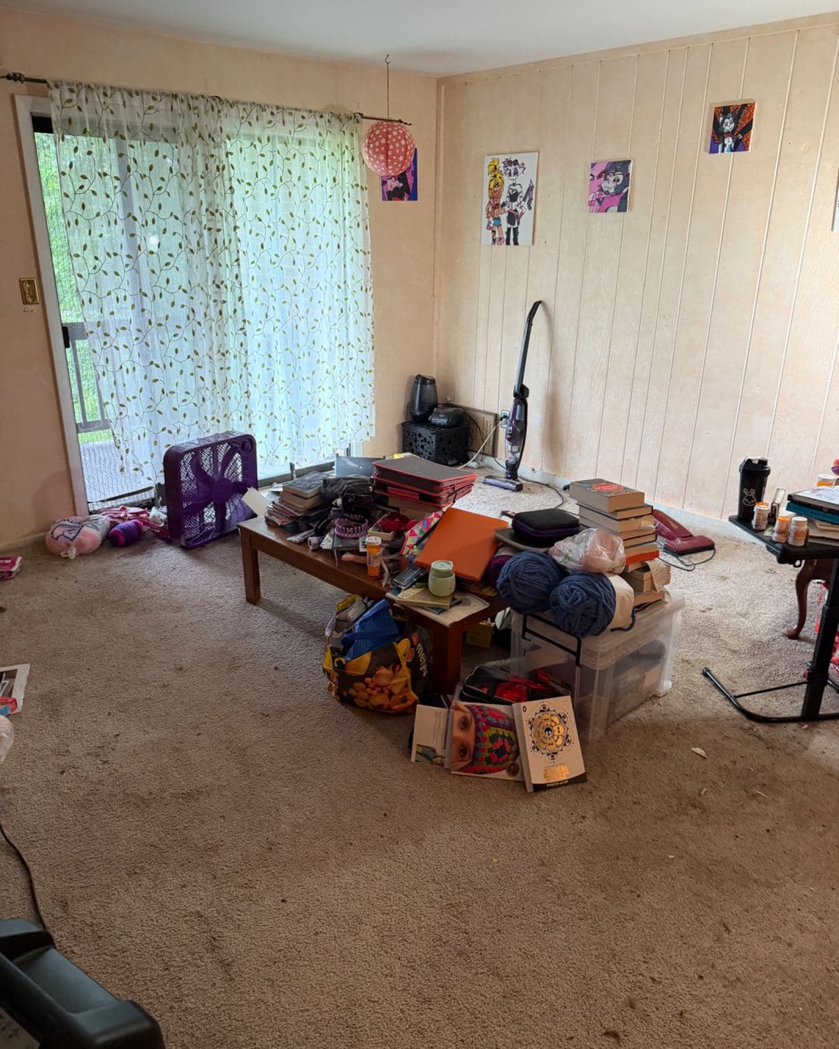 Living room before cleanup, belongings piled on a coffee table and the stained carpet
